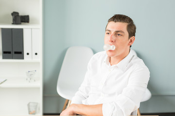 Fototapeta premium Joke, humor, office, people concept - man chewing the gum while he is working, gum splitted