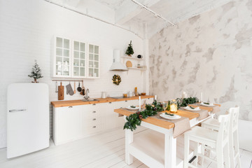 Loft style Apartment, large spacious living room with dining table and kitchen. Room with Christmas tree. Light white brick wall.