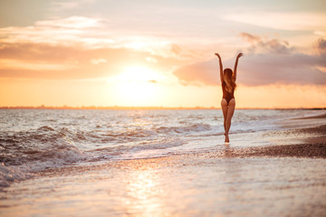 Obraz na płótnie Canvas carefree woman dancing in the sunset on the beach. vacation vitality healthy living concept