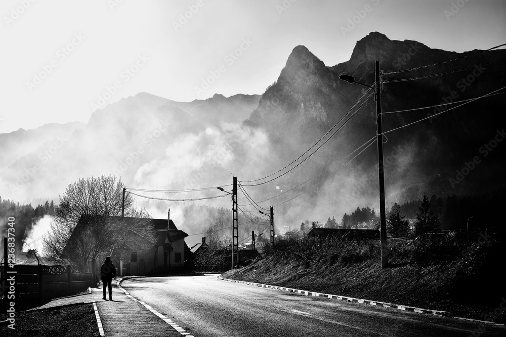 Sticker Beautiful misty landscape in well known Busteni mountain resort with Caraiman mountains in the background, Prahova Valley, Romania. Street photography, black and white creative image.