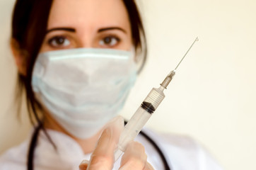 Young female doctor holds syringe for injection close up copy space