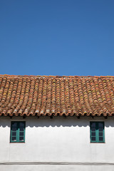 Red tile roof on an old Spanish building, with a blue sky background