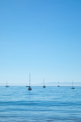 Anchored sailboat silhouettes on a calm ocean horizon 