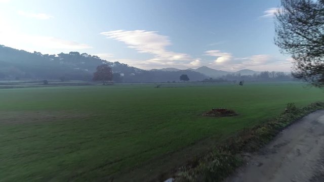 4K drone footage of flight over green fields in the morning in Catalonia