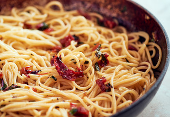 Homemade italian pasta with dried tomatoes in a pan