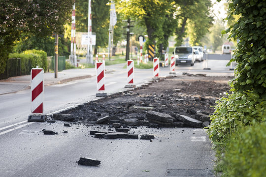Hałda zerwanego skruszonego asfaltu i pachołki drogowe na odgrodzonym pasie ruchu w mieście