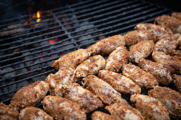 Arrangement of spicy chicken wings grilling on a charcoal barbecue, with space for text on top