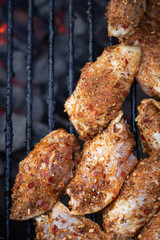 Close up on spicy chicken wings grilling on a charcoal barbecue