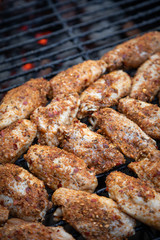 Close up on an arrangement of spicy chicken wings grilling on a charcoal barbecue