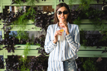 Beautiful young woman with plastic cup of fresh cocktail