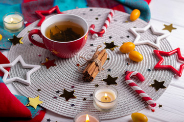 Tea, christmas decor, cinnamon sticks, stars confetti on white table background.