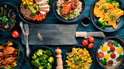 Assortment of food. Salad, avocado, quail, mushrooms, pumpkin. On a blue wooden background. Top...