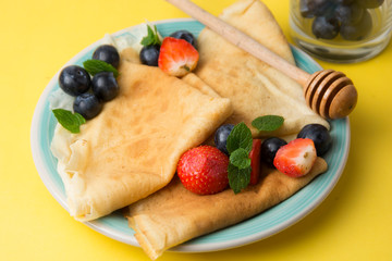 Homemade pancakes on a plate with blueberries and strawberries.