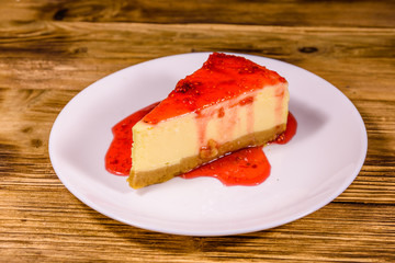 White plate with cheesecake New York and raspberry jam on wooden table