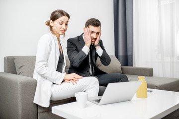 Fototapeta premium Businessman and woman having a problem sitting together with frustrated emotions on the couch at home or comfortable office