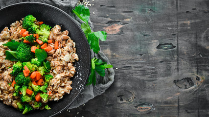 A plate of healthy food. Oatmeal with broccoli, carrots and parsley. Top view. On a black background. Free copy space.