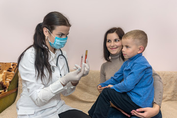 Doctor with medication in syringe and boy with mother