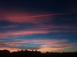 City skyline after sunset with colorful contrails