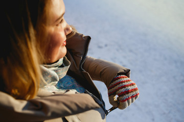 We warm. Woman zips up her jacket on a sunny winter day