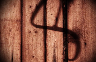 Spooky shadow of a hook on wooden wall