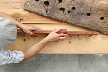 hands carpenter working a wooden rustic old board with a sand paper, top view and copy space template