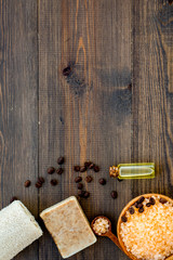 Aromatherapy and spa concept. Spa salt with coffee scent near soap and loofah on dark wooden background top view copy space
