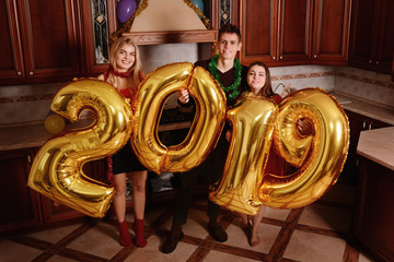 New 2019 Year is coming. Group of cheerful young people carrying gold colored numbers and have fun at the party