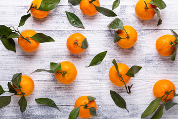 Fresh orange mandarins, tangerine with green leaves on white wooden background. Top view