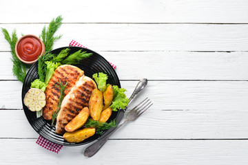Baked chicken fillet with carrot and vegetables on a white wooden background. Top view. Free copy space.