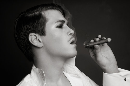 Vintage style duotone portrait of young beautiful sexy man smoking sigar
