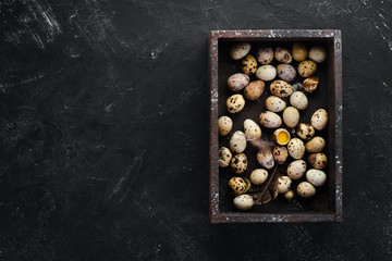 Quail eggs in a wooden box. On the old background. Top view. Free copy space.