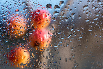 Autumn paint behind the glass with drops from the rain. Abstract background.