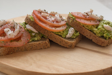 Tomato avocado toast on wooden board. Health breakfast or snack concept. Food photography concept. Copy space.