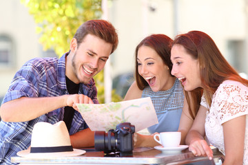 Three happy tourists checking guide in a coffee shop