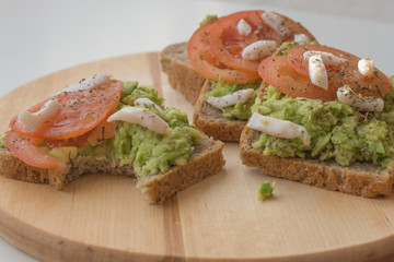 Toast with avocado and tomato, bitten one. Health breakfast or snack concept. Food photography concept. Copy space.