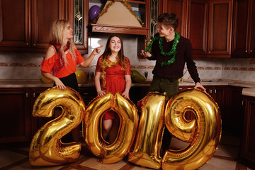 New 2019 Year is coming. Group of cheerful young people carrying gold colored numbers and have fun at the party