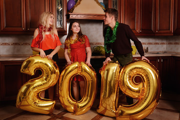New 2019 Year is coming. Group of cheerful young people carrying gold colored numbers and have fun at the party