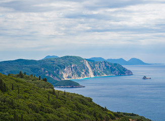 Fototapeta na wymiar View on cllifs, forest and green hill and turquoise blue sea at Paleokastritsa bay, summer cloudy sky, Corfu, Kerkyra, Greece