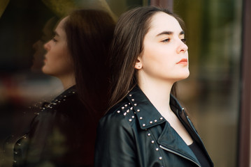 Portrait young punk rock fashion girl in black leather jacket with stilettos in an urban...
