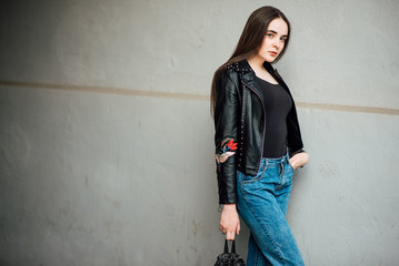 Portrait young punk rock fashion girl in a black leather jacket with stilettos in an urban...