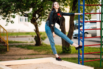 Portrait young punk rock fashion girl in black leather jacket with stiletto in a street warehouse...