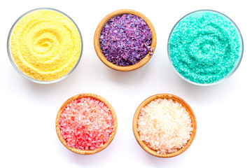 Spa salt background. Colorful spa salt in bowls on white background top view. Yellow, turquoise, pink, purple spa salt