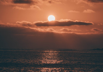 Sun resting on the clouds on a sunset in the Pacific Ocean
