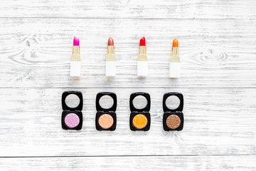 visagiste desk with decorative cosmetics: eyeshadows, lipstick wooden background top view