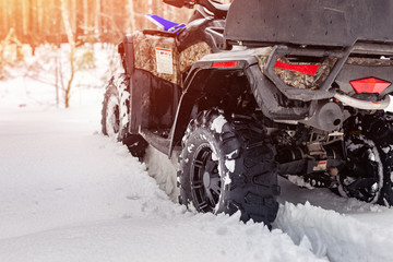 Close-up ATV 4wd quad bike in forest at winter. 4wd all-terreain vehicle stand in heavy snow with...