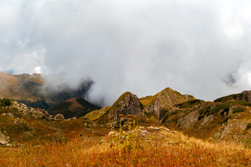 rocky mountain plateau with dry grass and clouds in the background