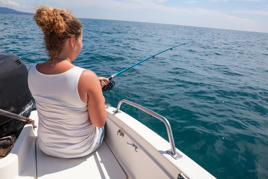 Woman Fishing With Trolling Catch On Boat Deck, Rear View