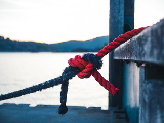 Two different colored ropes tied together at a mooring - 236854347