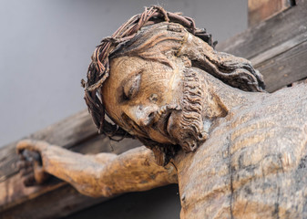 Holy Crucified Jesus Christ close-up. Ancient wooden sculpture. Bottom view. Sacred figure.
