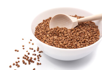 Buckwheat in a white bowl with a spoon. Isolated on white background.